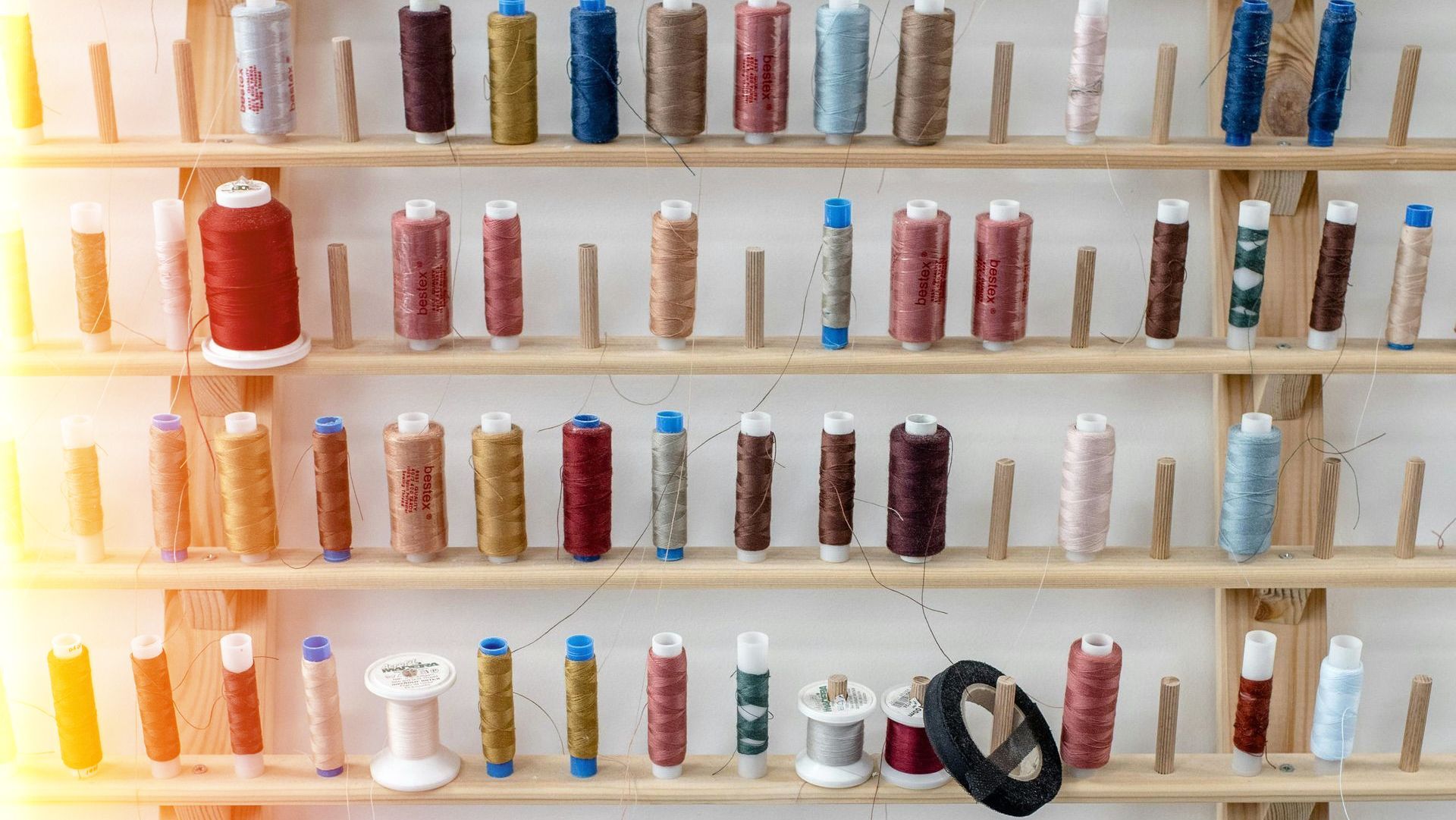 A shelf filled with spools of thread of different colors.