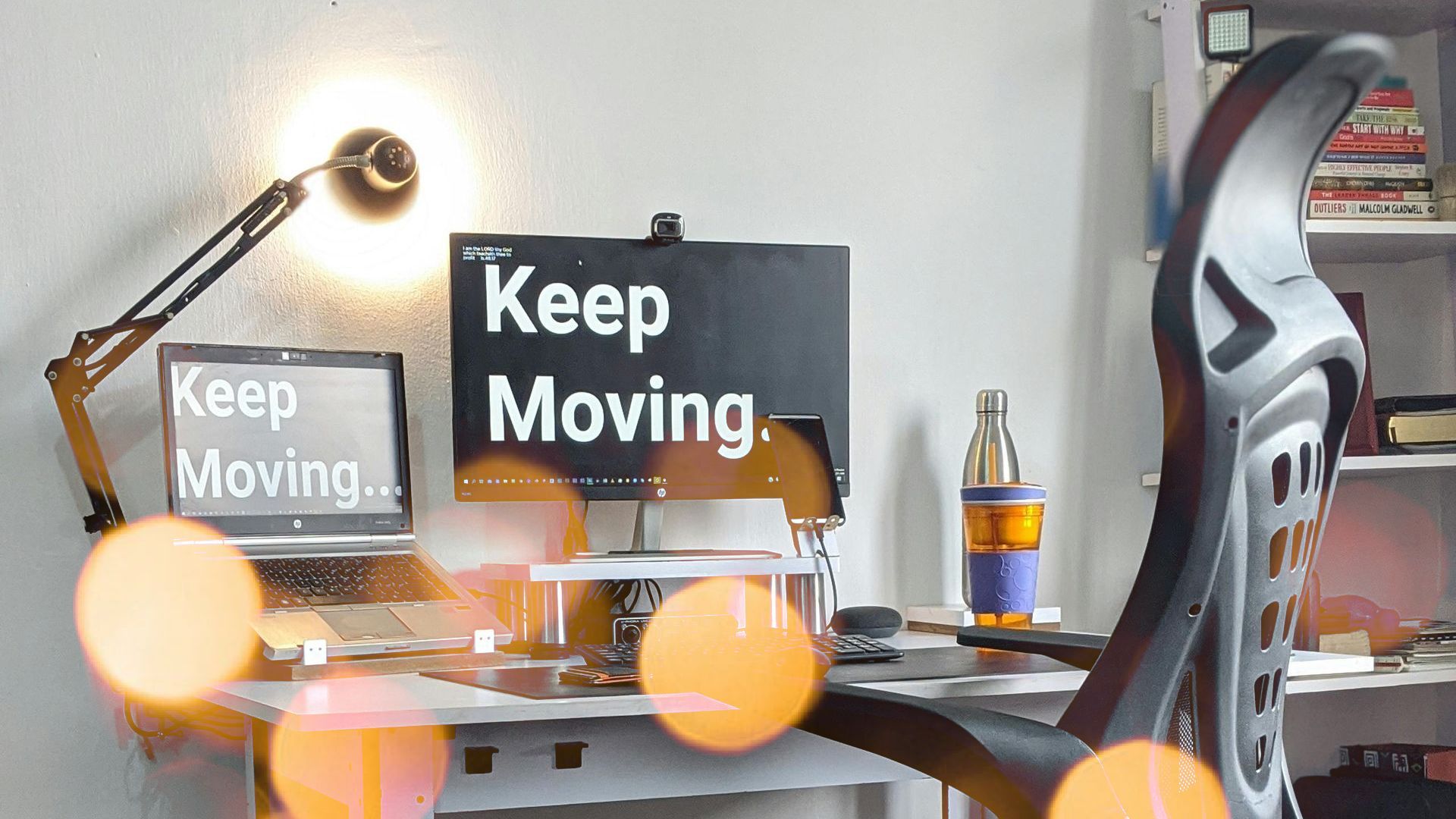 A desk with a computer and a sign that says keep moving