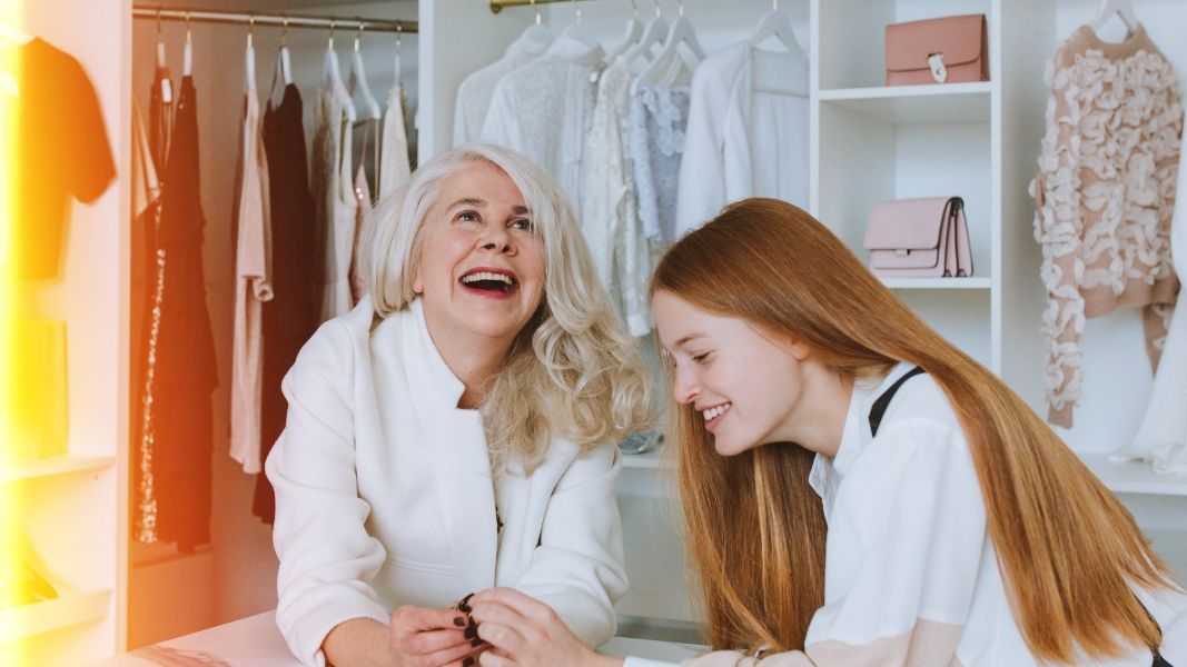 two women are laughing in front of a closet full of clothes