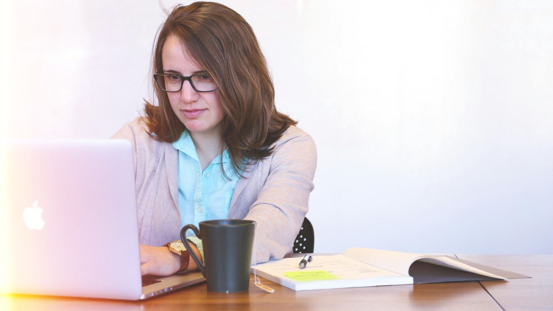 A woman is sitting at a table using a laptop computer.