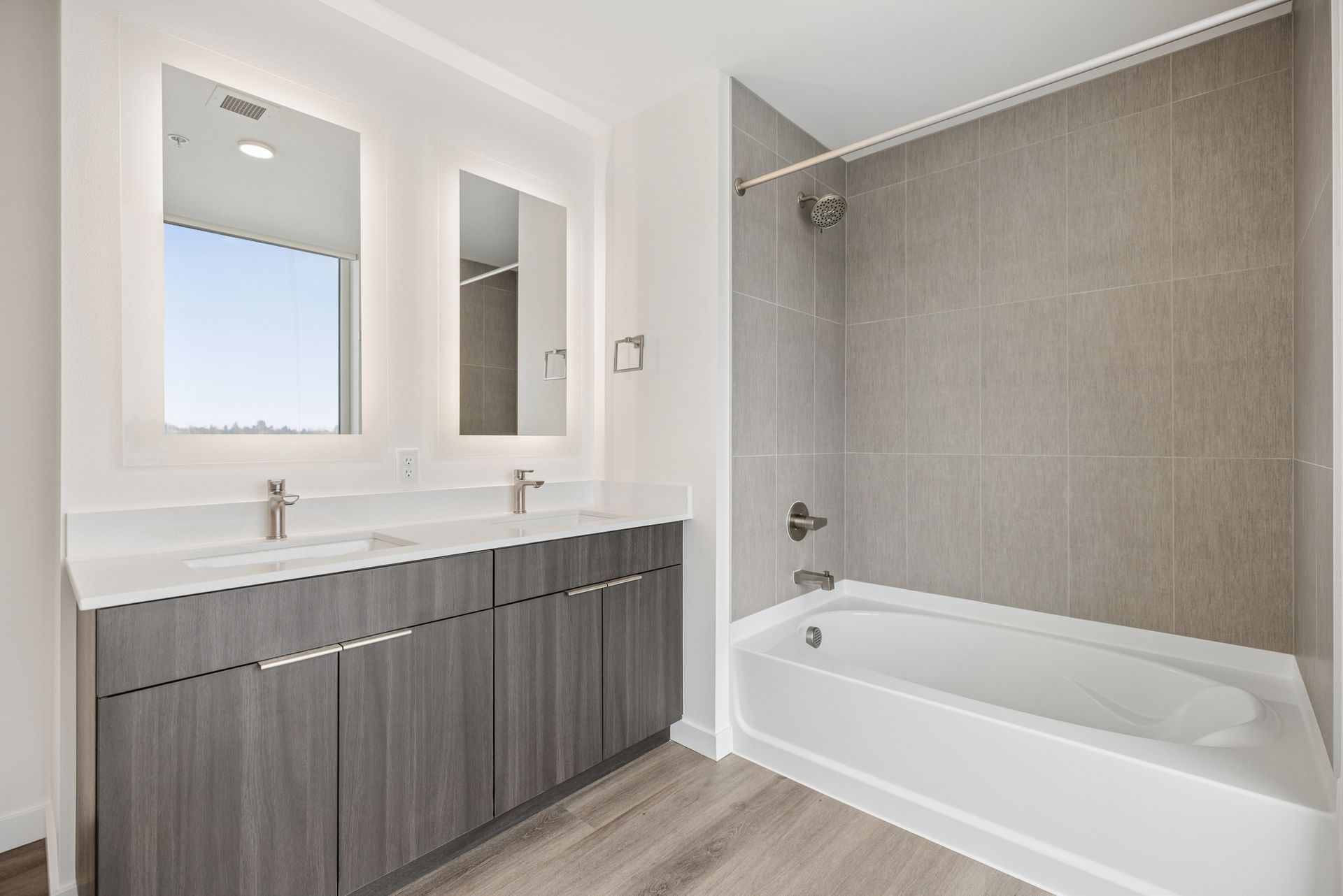 Modern bathroom with double vanity, large mirror, and tiled bathtub/shower combo