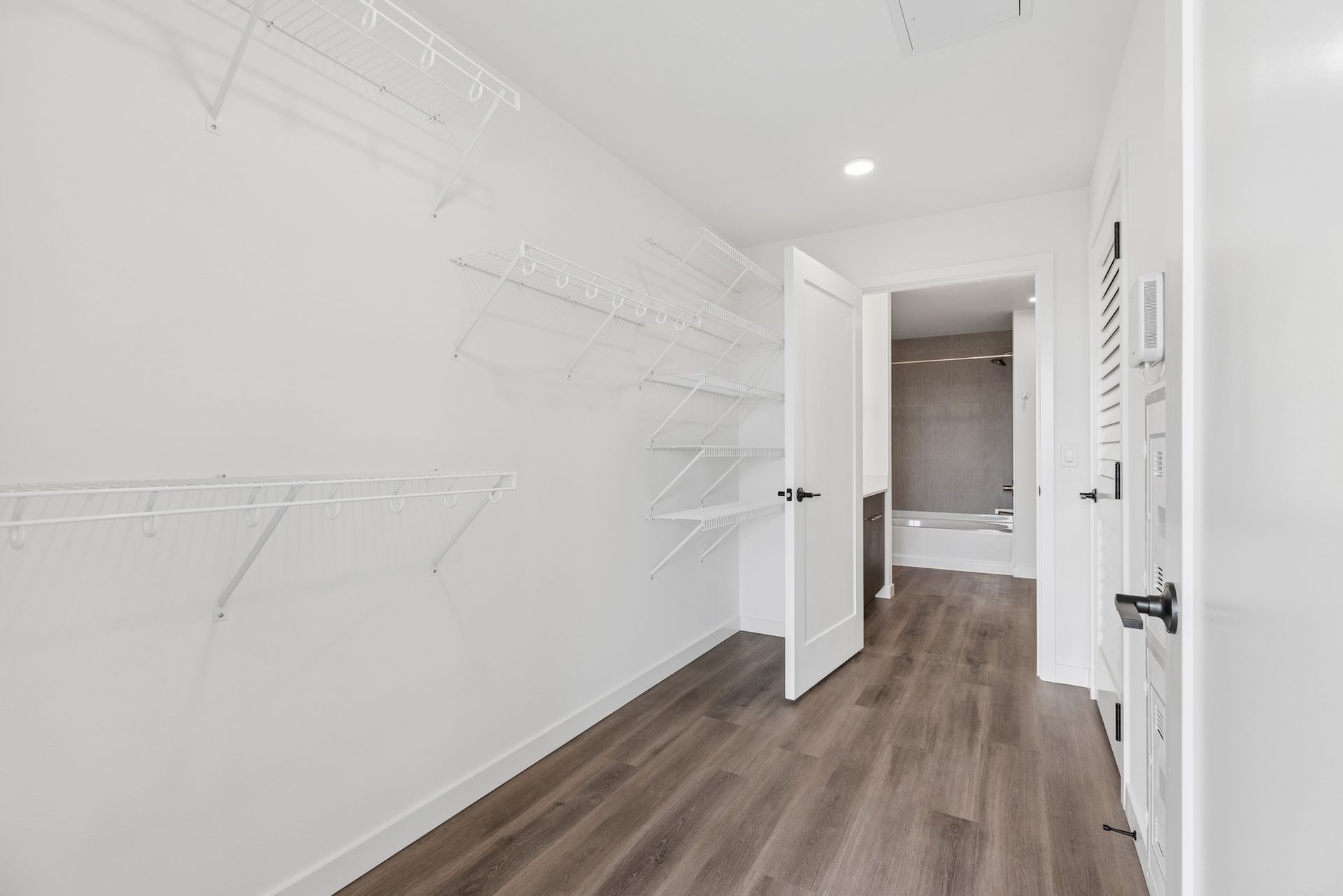 Empty white hallway with wood floor and wall-mounted coat hooks