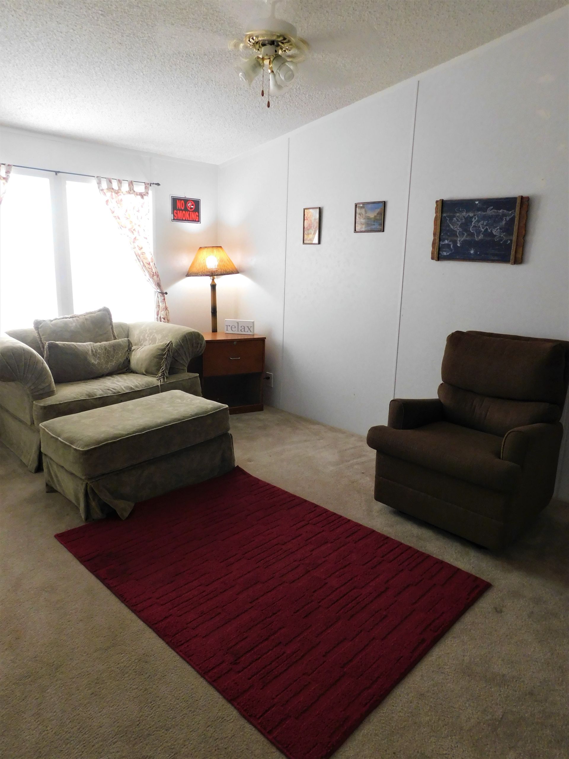 Living room with sofa, ottoman, chair, rug, lamp, and art on the wall.