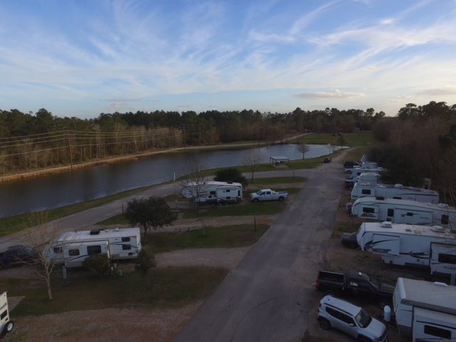 RV park with trailers parked along a road near a lake, under a partly cloudy sky.