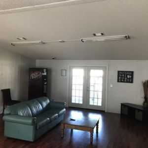 Living room with a green couch, wooden coffee table, and a soda machine. French doors and hardwood floors.