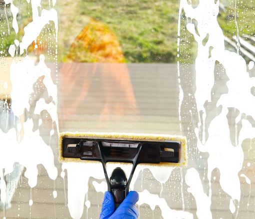 A person is cleaning a window with a squeegee.