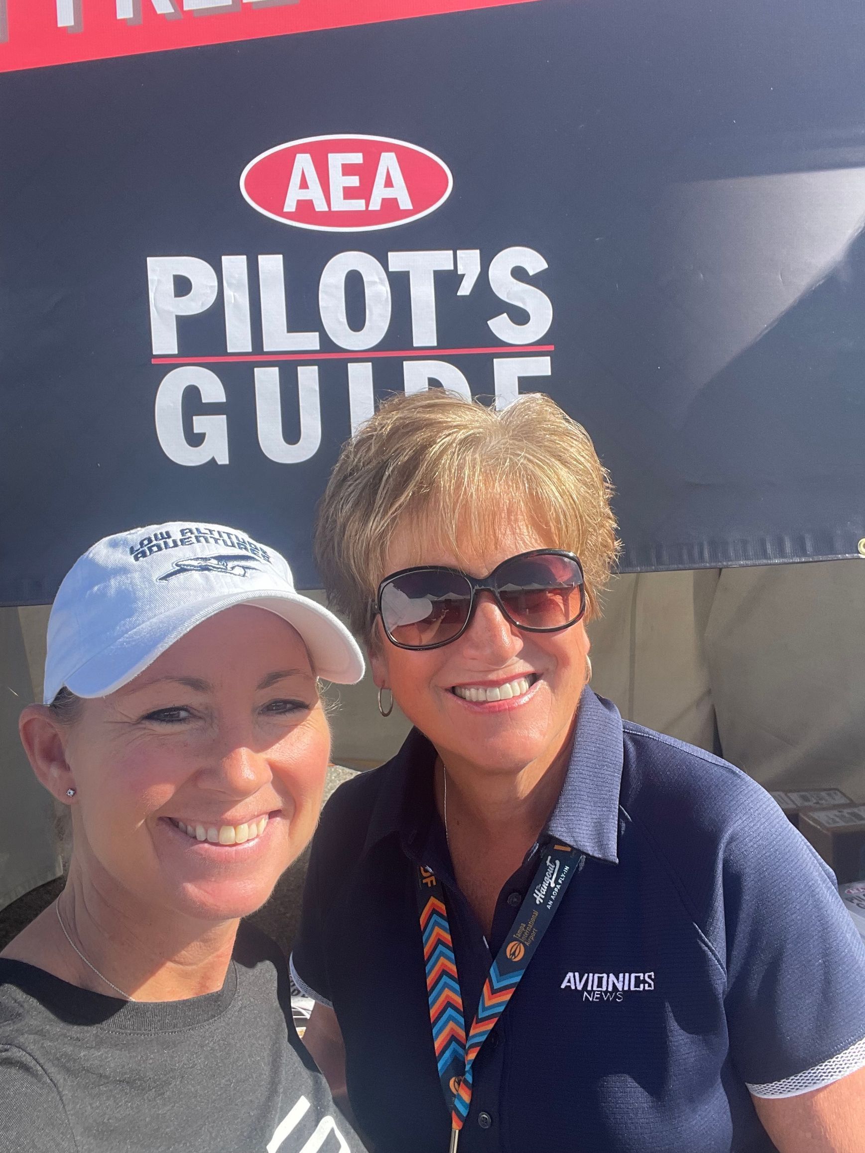 Two women are posing for a picture in front of a pilot 's guide sign
