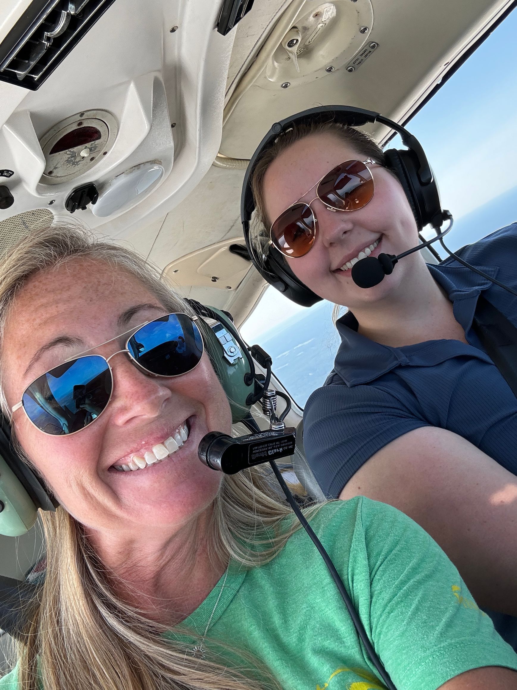 Jessica Power wearing sunglasses and headphones are sitting in a plane.