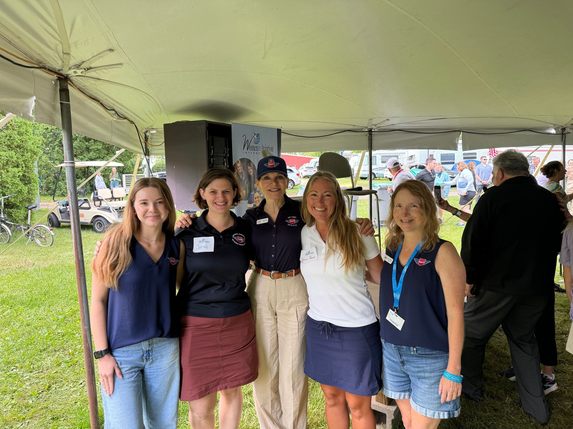 A group of women are posing for a picture under a tent.