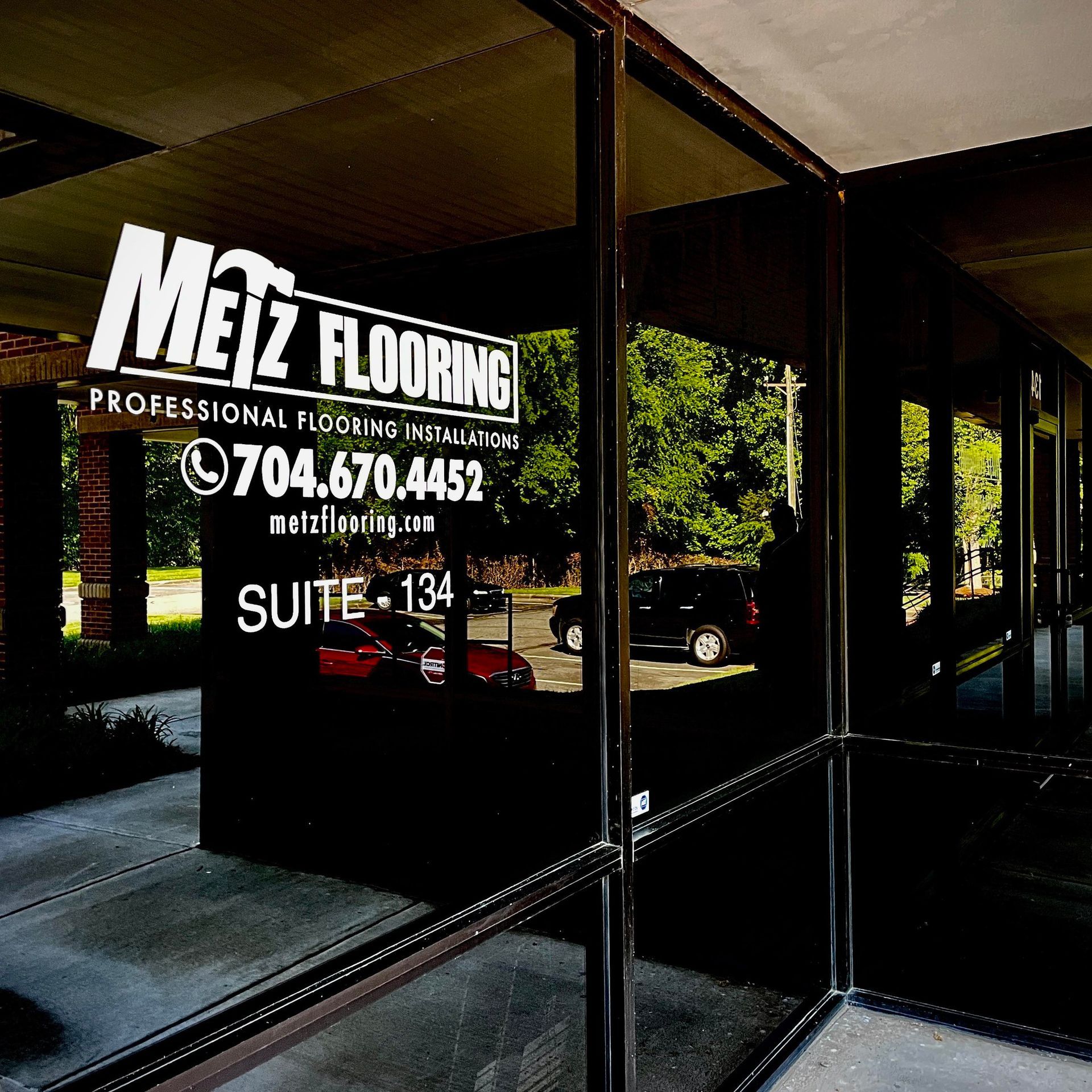 Exterior view of Metz Flooring suite, with signage on a dark glass window.