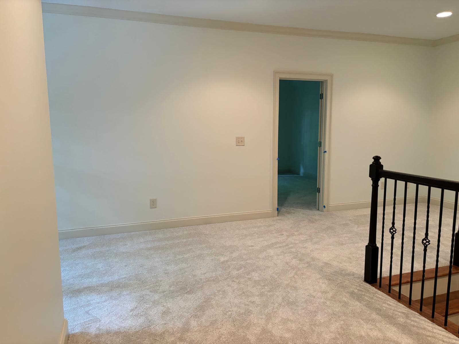 Interior view of a neutral-toned room with light carpet, white walls, and a doorway leading to another room.