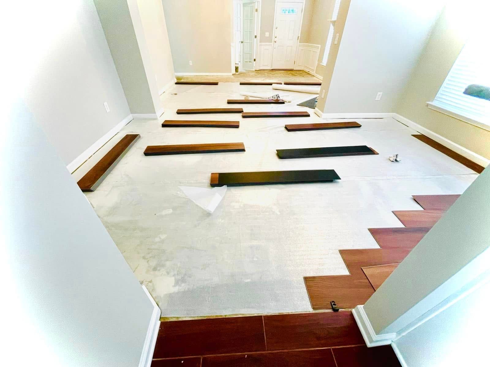 Hardwood flooring installation in progress: planks of wood scattered on a white surface, ready to be laid.