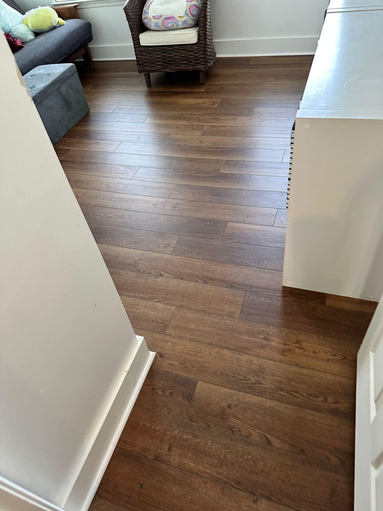 Wood-look flooring in a room, partially visible walls and furniture, creating a home interior.