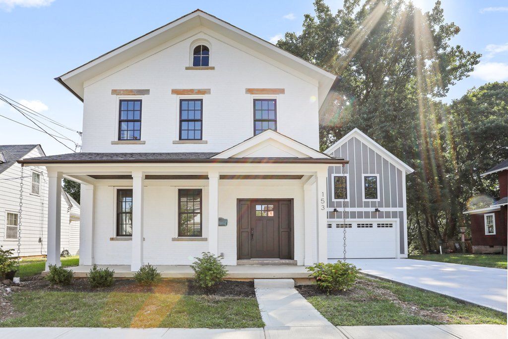 A white house with a brown door and a white garage