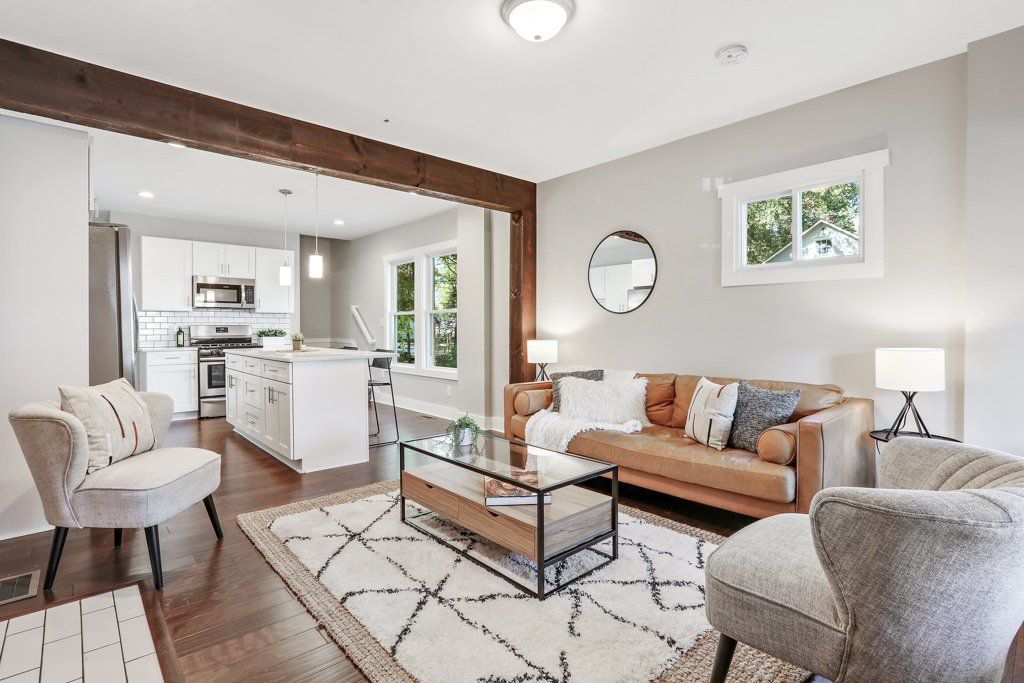 A living room with a brown couch and white chairs