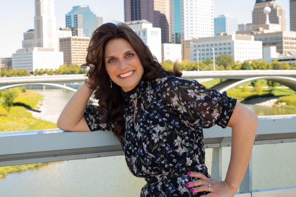 A woman leaning on a railing with a city in the background
