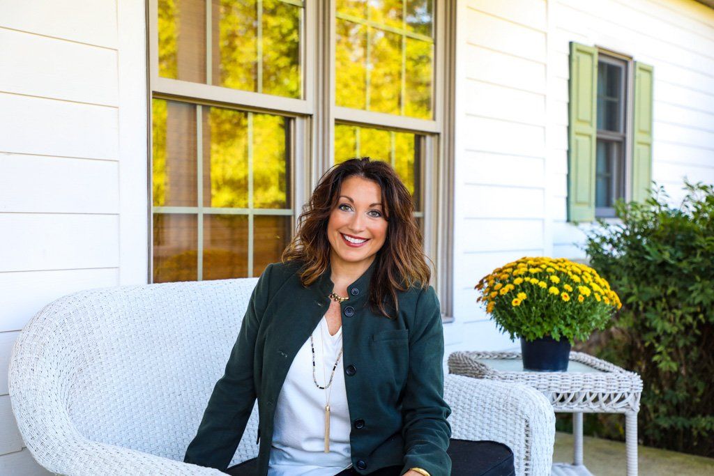A woman in a green jacket is sitting on a white couch
