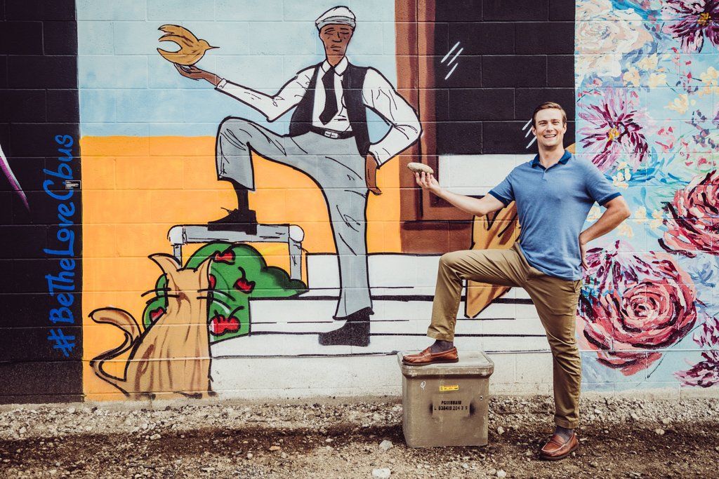 A man stands in front of a mural that says be the love bus