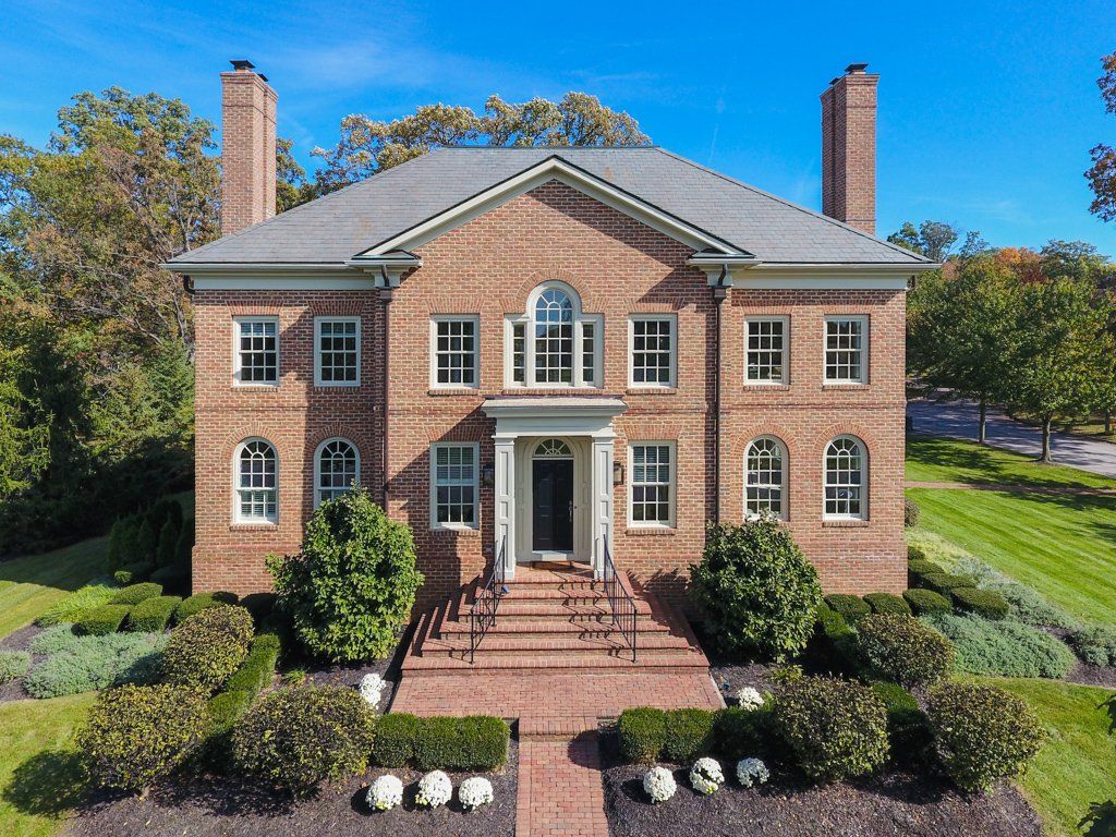 An aerial view of a large brick house with a gray roof