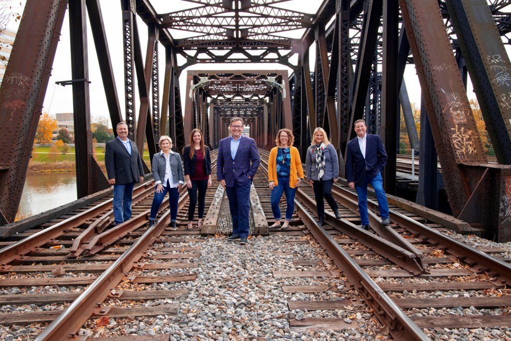 A group of people standing on train tracks in front of a bridge