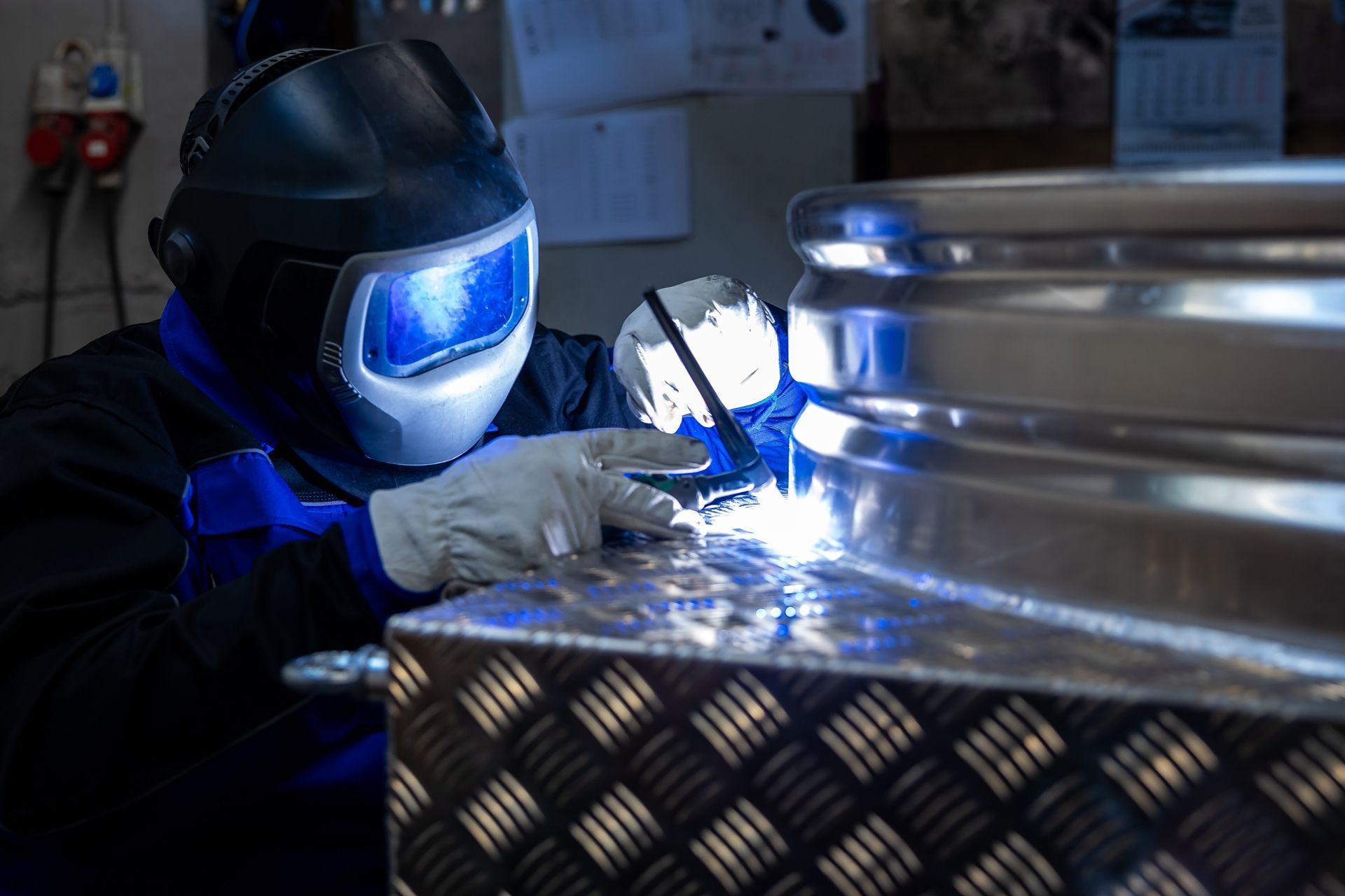 Welder in a protective mask welding metal in a workshop, sparks flying