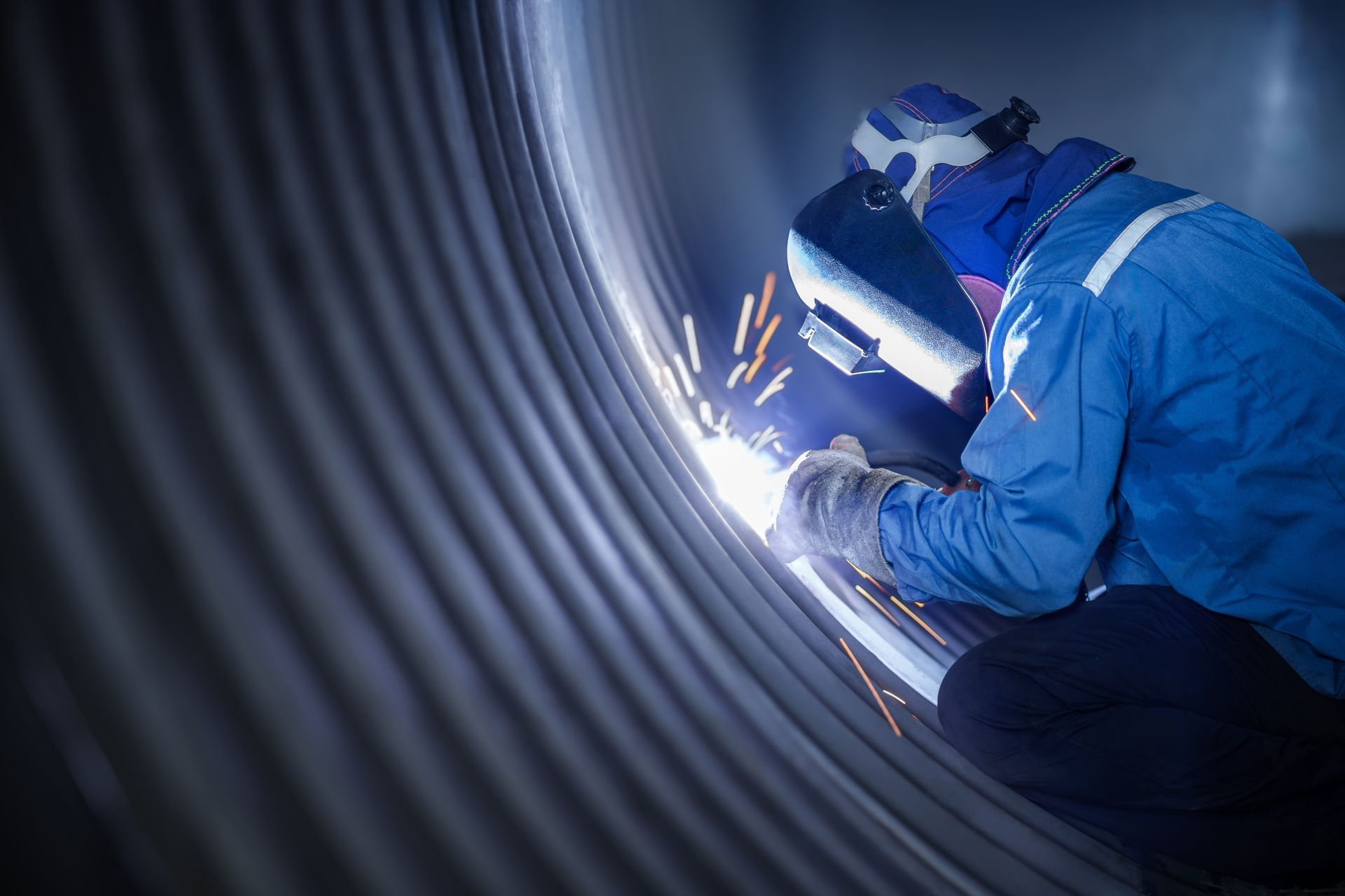 Welder wearing protective gear working on a large corrugated metal structure