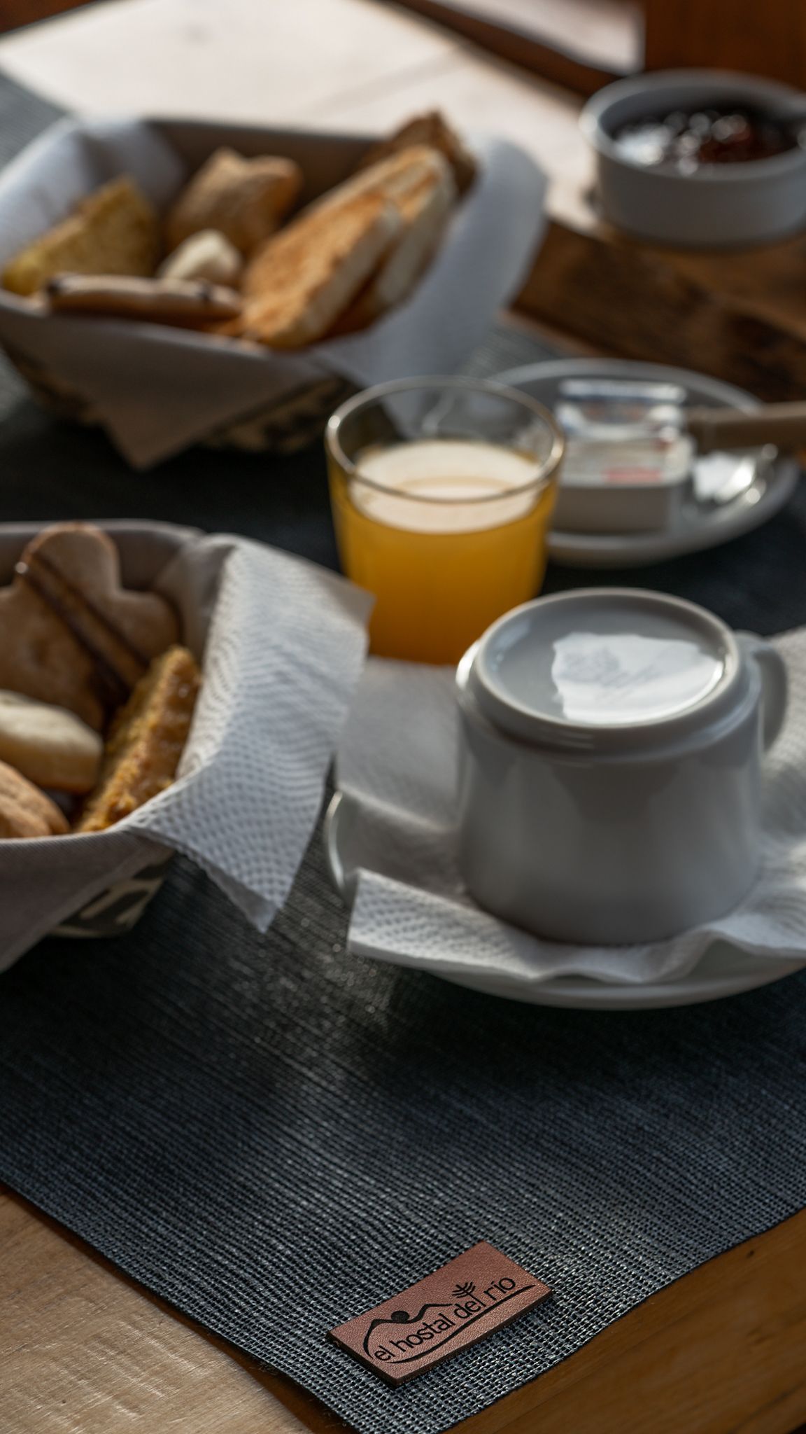 Una mesa con una canasta de pan, un vaso de jugo de naranja y una taza de café.