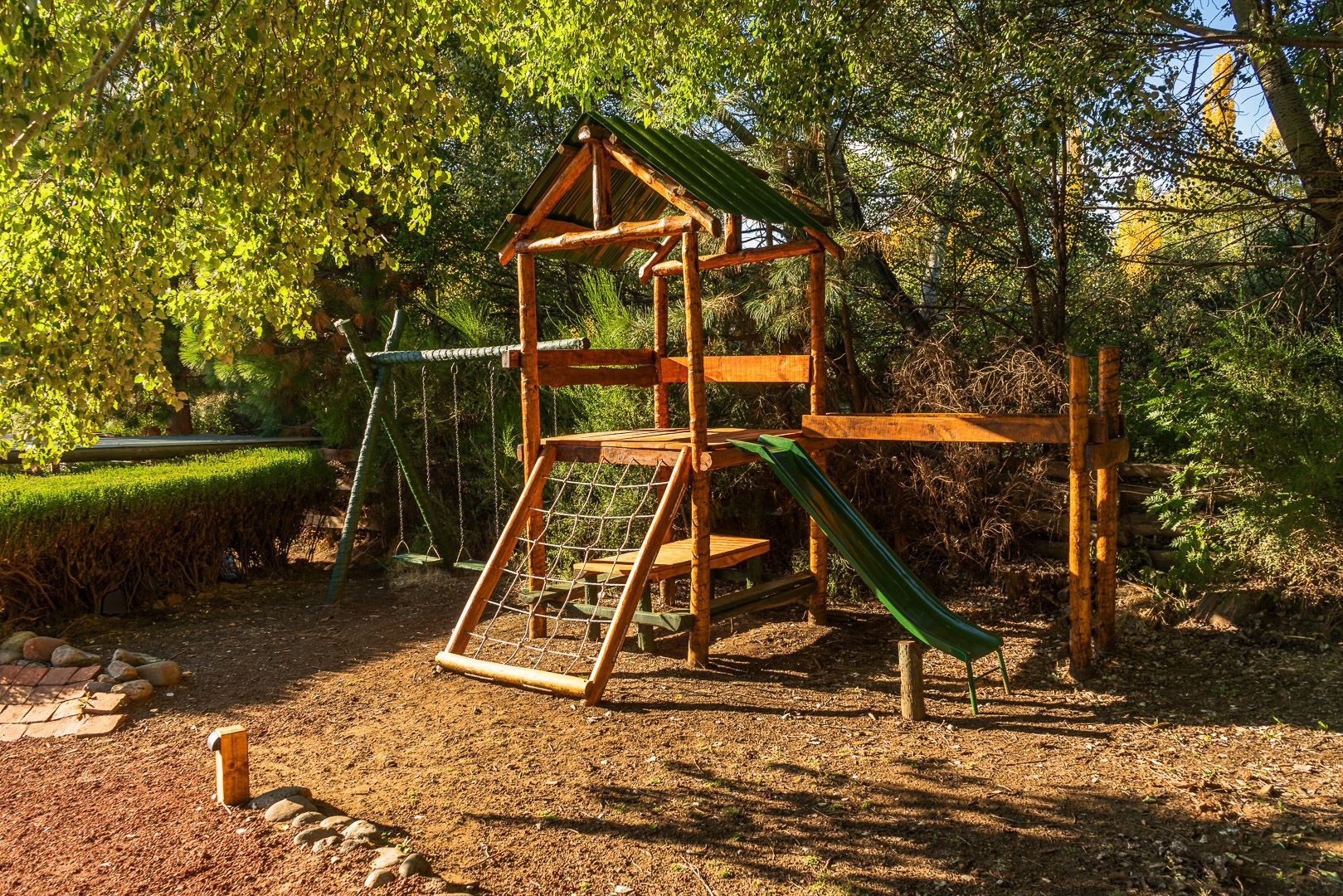 Un parque infantil de madera con tobogán y columpios en el bosque.