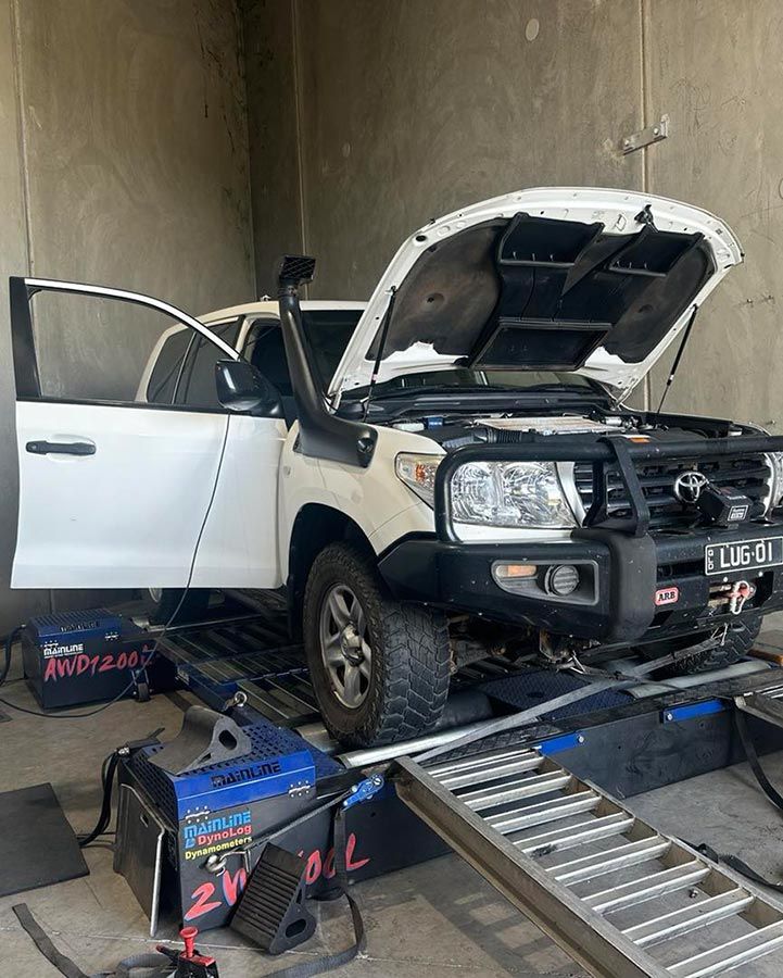 A White Truck With The Hood Up Is Sitting On A Ramp In A Garage — Dieselflash Whitsundays in Cannonvale, QLD