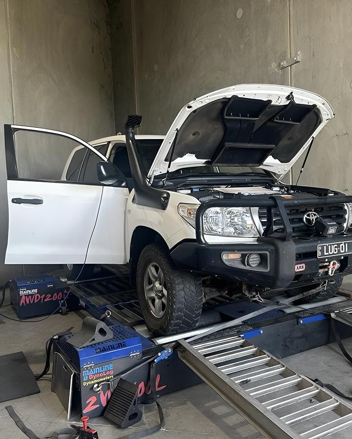 A White Truck With The Hood Up Is Sitting On A Ramp In A Garage — Dieselflash Whitsundays in Cannonvale, QLD