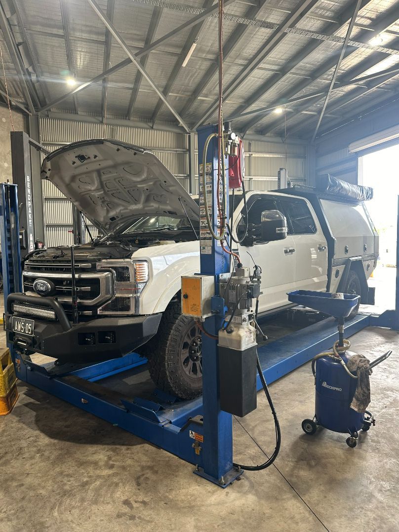 A White Truck is Sitting on a Lift in a Garage — Dieselflash Whitsundays in Proserpine, QLD