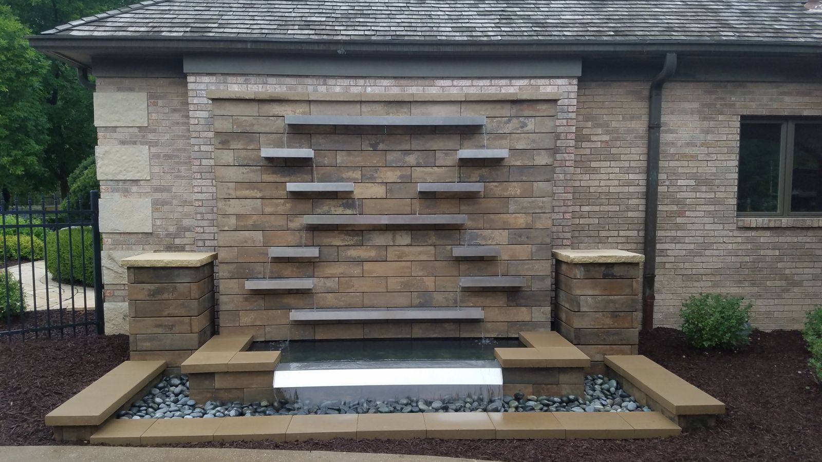 A brick wall with a waterfall in front of it