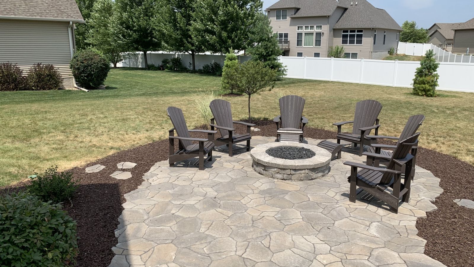 A fire pit with chairs around it in a backyard.