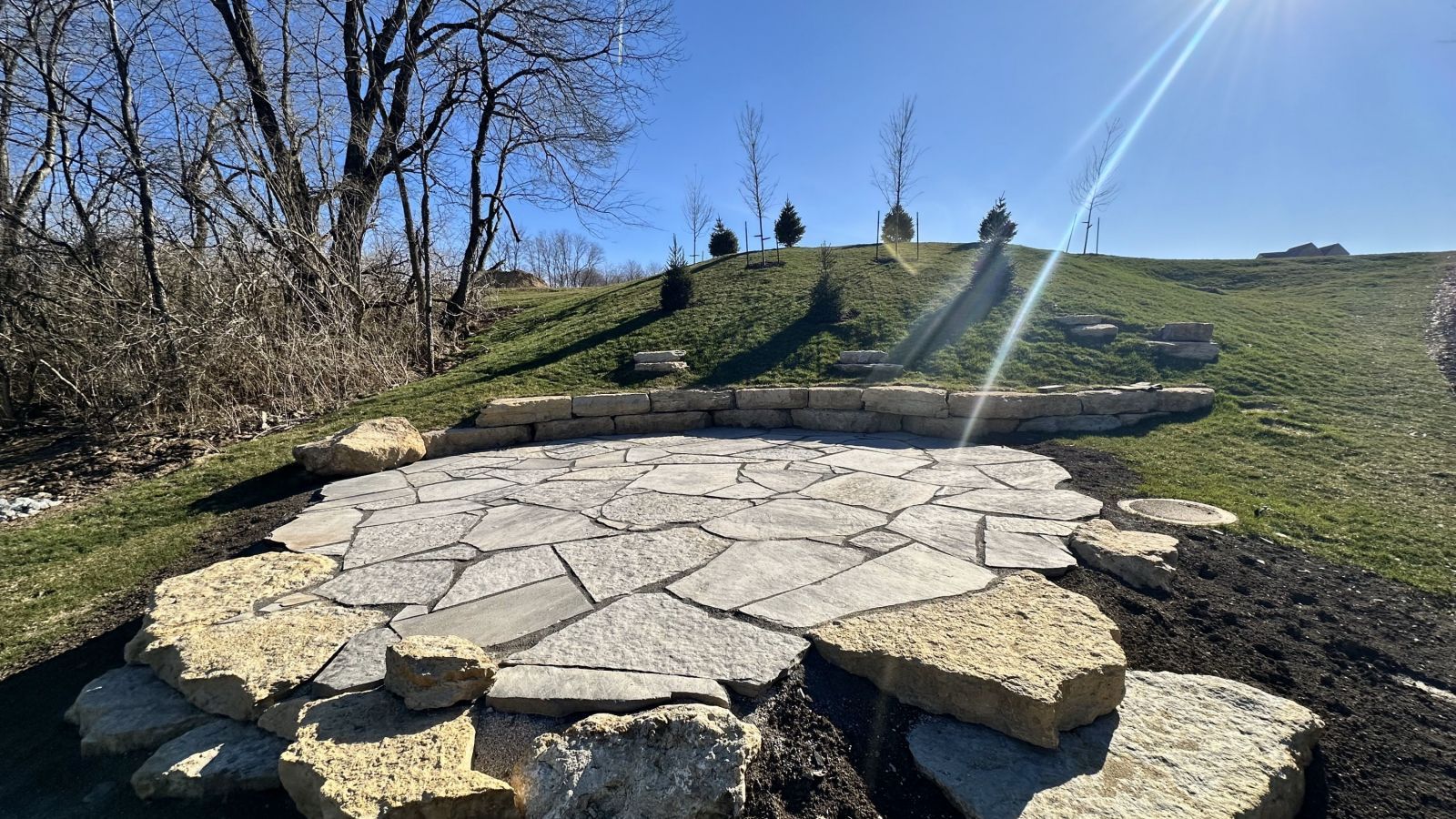A stone patio is being built in the middle of a grassy field.
