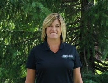 A woman in a black shirt is standing in front of a tree.