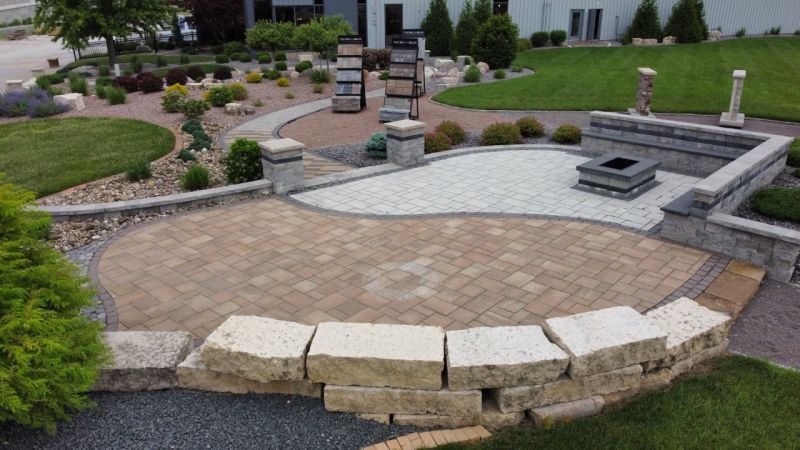 A patio with bricks and a stone wall in a garden.