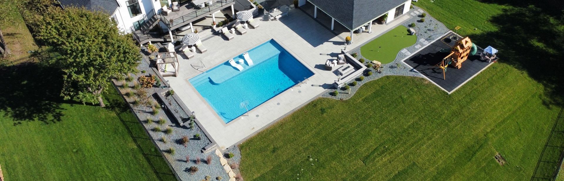 An aerial view of a house with a large swimming pool in the backyard.