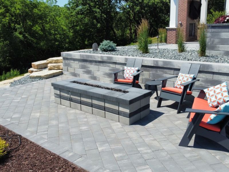 Outdoor patio with a block fire pit, seating area, and retaining wall.