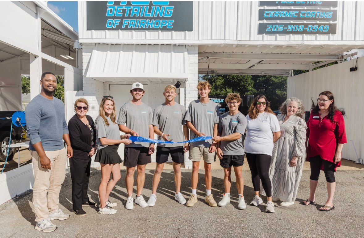 People cutting a blue ribbon in front of a building with the words 