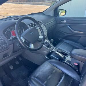 Interno di un'auto Ford nera, in cui si vedono il cruscotto, il volante e i sedili anteriori.