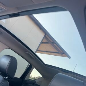 Dentro un'auto, con il tettuccio apribile aperto, guardo il cielo e il bordo di un edificio.