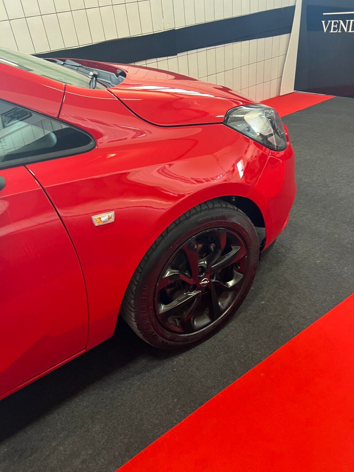 Pannello anteriore di un'auto rossa con uno pneumatico nero su un pavimento rosso.