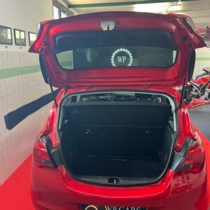 Auto rossa con bagagliaio aperto. Interni visibili; logo sul lunotto posteriore.