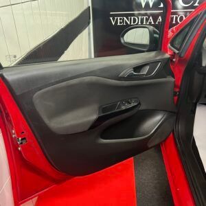 Interno portiera auto rosso; pannello nero con comandi e maniglia, portiera aperta.