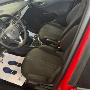 Interno di un'auto Opel rossa, sedili, volante e cruscotto neri. Tappetino