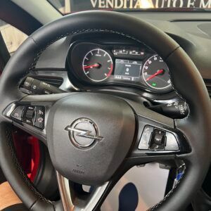 Volante nero con logo Opel e cruscotto con indicatori rossi.