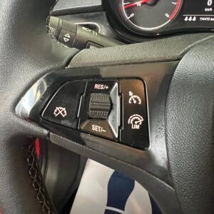 Primo piano del volante di un'auto con i pulsanti del cruise control e del limitatore di velocità.