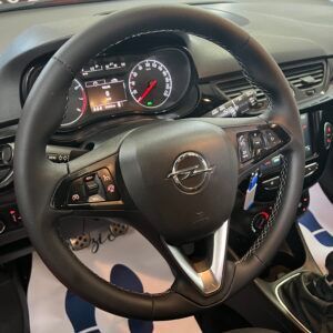 Volante nero di un'auto, con logo Opel e comandi.