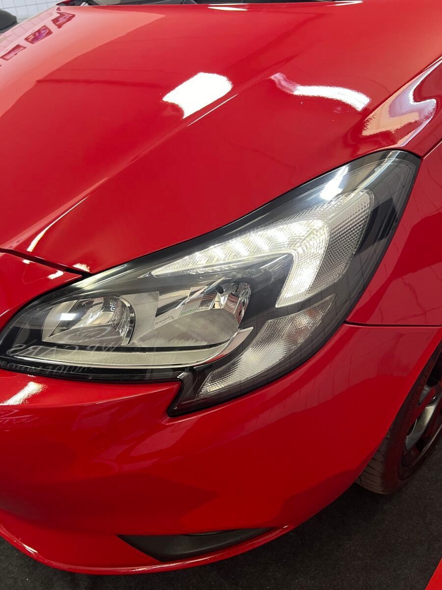 Faro rosso di un'auto, rifiniture nere, in contrasto con il cofano rosso.