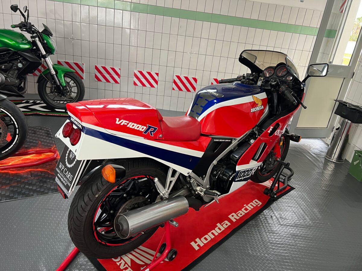 Motocicletta Honda VFR750F rossa, bianca e blu su un supporto in un garage.